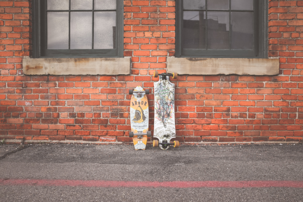 Skates apoiados em uma parede de tijolo laranja